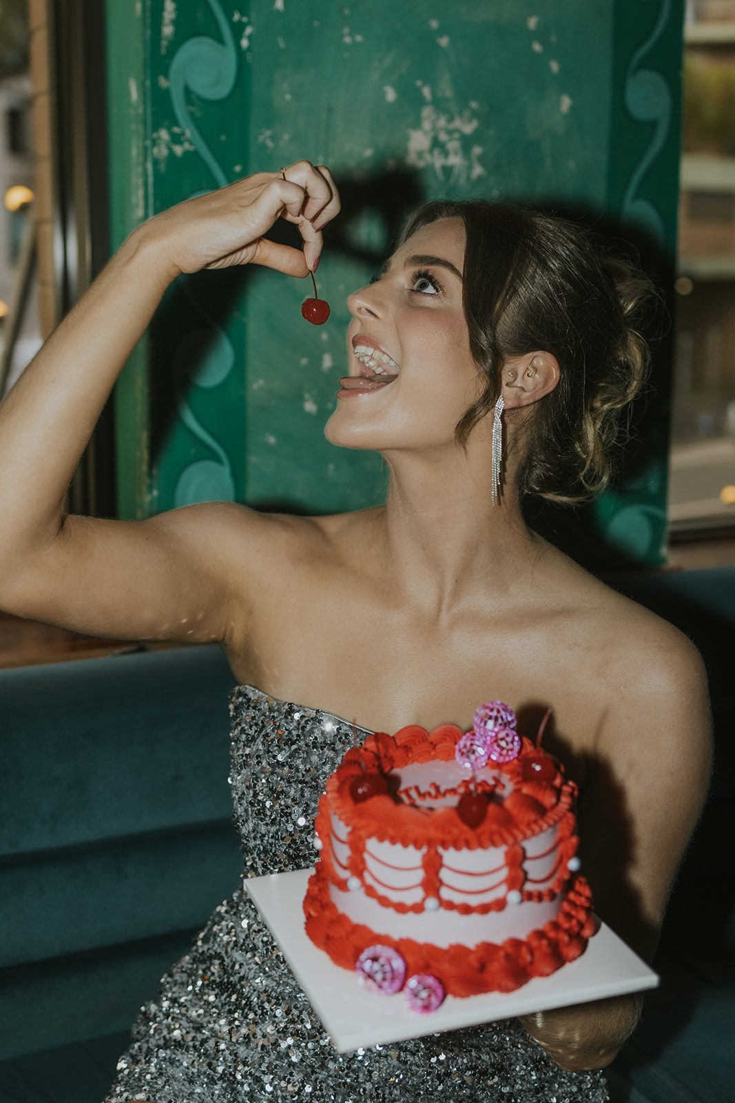 birthday girl eating cherry holding red vintage birthday cake at hotel harry in sydney australia