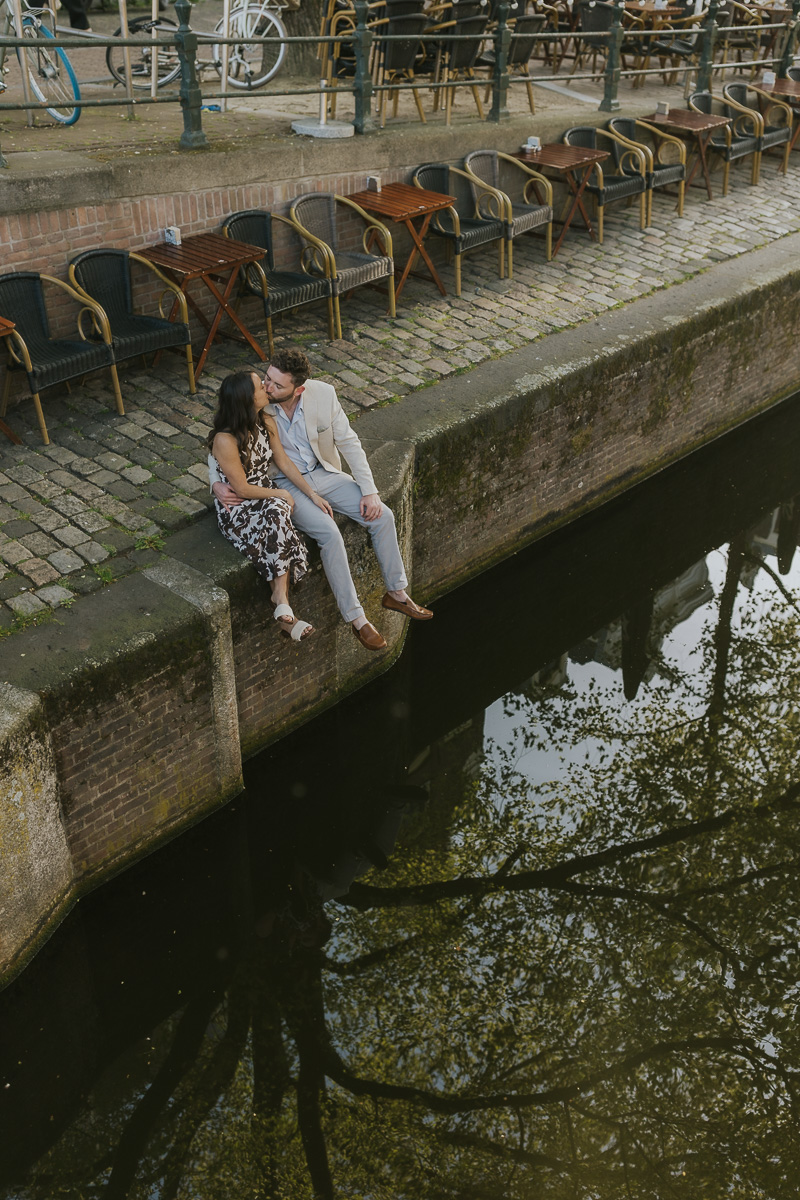 couples kissing sitting along the canals of amsterdam