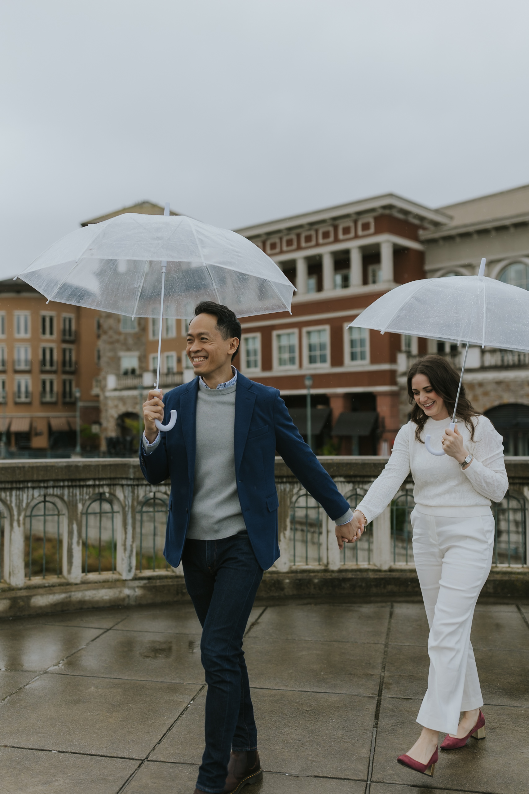 bride and groom running through the rain with umbrellas along the riverfront in downtown napa