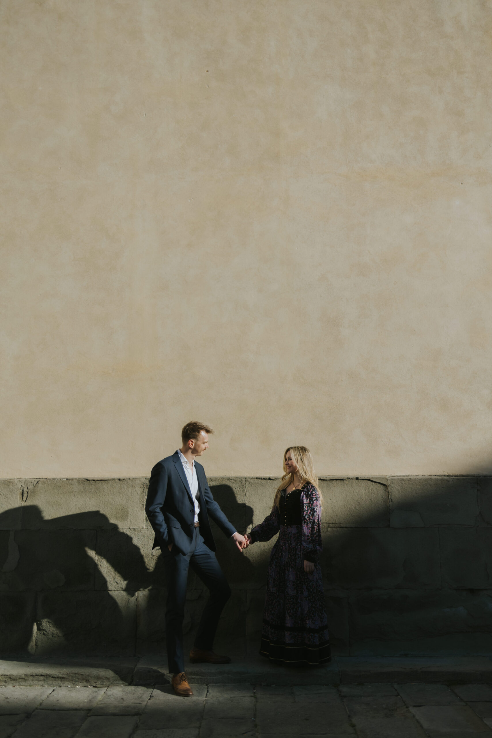 couple holding hands looking at each other in the dramatic morning light in florence italy